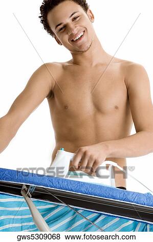 Low angle view of a young man ironing View Large Photo Image Stock Photo - Low angle view of a young man ironing. Fotosearch
