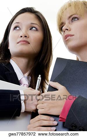 Low angle view of two businesswomen holding a laptop and a file View Large Photo Image Stock Image - Low angle view of two businesswomen holding a laptop and a file. Fotosearch