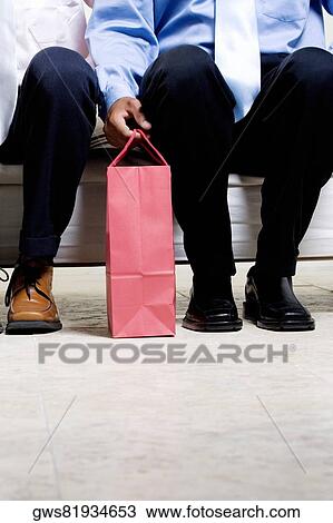 Low section view of two businessmen sitting with a shopping bag View Large Photo Image Stock Image - Low section view of two businessmen sitting with a shopping bag. Fotosearch