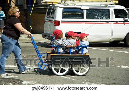 Stock Image - Mid adult woman pushing children in a trolley. Fotosearch