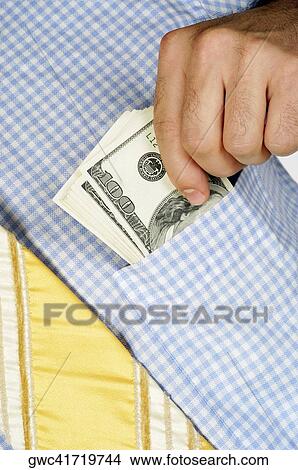 Picture - Mid section view of a businessman putting money into his shirt pocket. Fotosearch