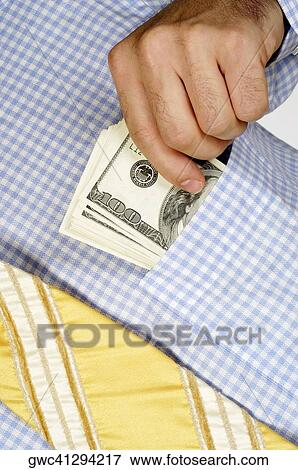Stock Photo - Mid section view of a businessman putting money into his shirt pocket. Fotosearch