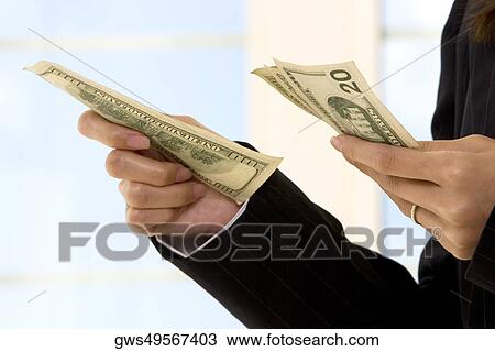 Stock Image - Mid section view of a businesswoman holding American paper currency. Fotosearch