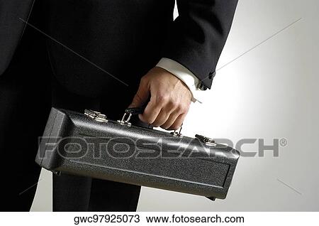 Stock Image - Mid section view of a man holding a case. Fotosearch