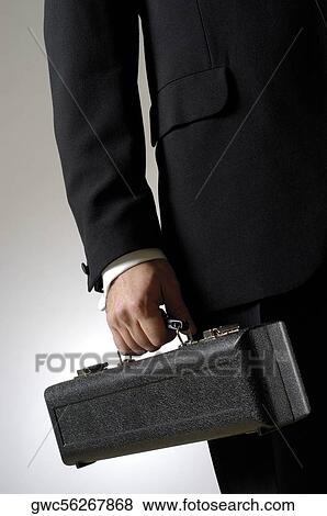 Stock Photo - Mid section view of a man holding a case. Fotosearch