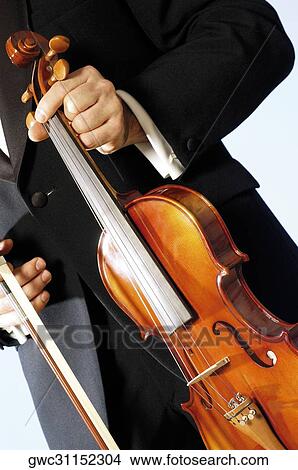 Mid section view of a musician holding a violin View Large Photo Image Picture - Mid section view of a musician holding a violin. Fotosearch