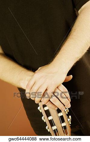 Mid section view of a musician holding an acoustic guitar View Large Photo Image Stock Photo - Mid section view of a musician holding an acoustic guitar. Fotosearch