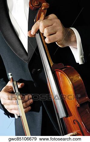 Mid section view of a musician holding a violin and a bow View Large Photo Image Stock Photo - Mid section view of a musician holding a violin and a bow. Fotosearch