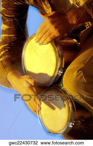 Stock Image - Mid section view of a musician playing the bongo. Fotosearch
