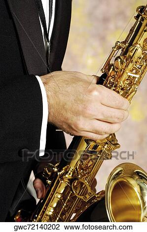 Stock Image - Mid section view of a musician playing the saxophone. Fotosearch