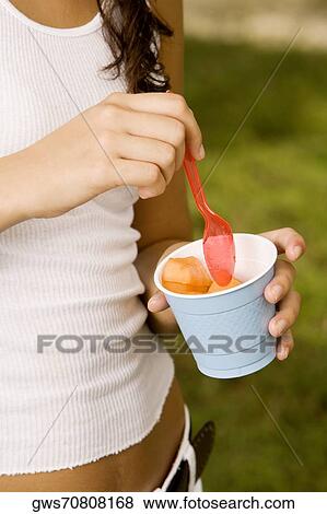 Mid section view of a teenage girl holding a disposable cup and a plastic spoon View Large Photo Image Stock Photo - Mid section view of a teenage girl holding a disposable cup and a plastic spoon. Fotosearch