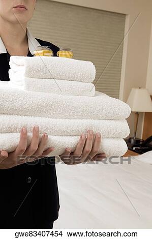 Mid section view of a waitress holding a stack of towels View Large Photo Image Picture - Mid section view of a waitress holding a stack of towels. Fotosearch