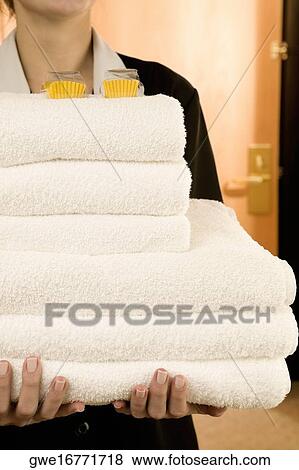 Stock Photo - Mid section view of a waitress holding a stack of towels. Fotosearch