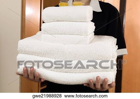 Stock Photo - Mid section view of a waitress holding a stack of towels. Fotosearch