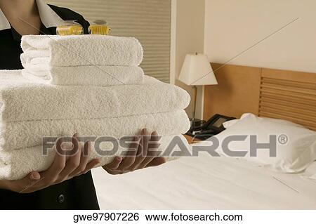 Stock Photograph - Mid section view of a waitress holding a stack of towels. Fotosearch