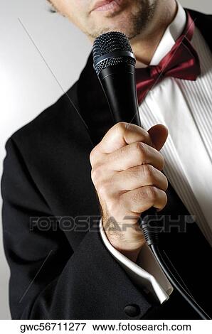 Mid section view of a young man holding a microphone View Large Photo Image Stock Photo - Mid section view of a young man holding a microphone. Fotosearch