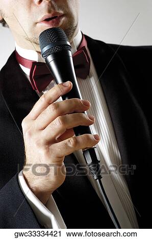 Mid section view of a young man singing into a microphone View Large Photo Image Stock Image - Mid section view of a young man singing into a microphone. Fotosearch