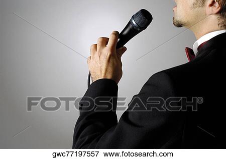 Mid section view of a young man singing into a microphone View Large Photo Image Stock Photo - Mid section view of a young man singing into a microphone. Fotosearch