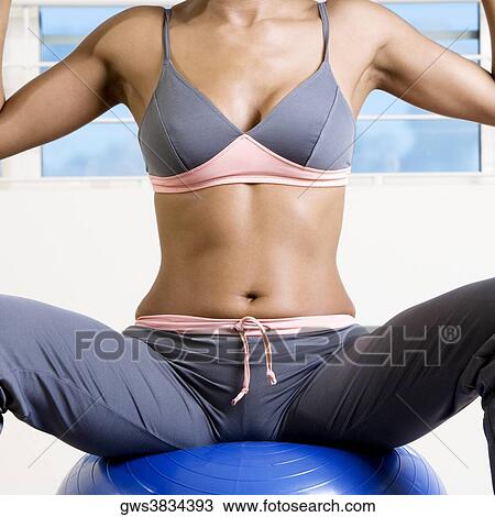 Mid section view of a young woman sitting on a fitness ball View Large Photo Image Stock Image - Mid section view of a young woman sitting on a fitness ball. Fotosearch