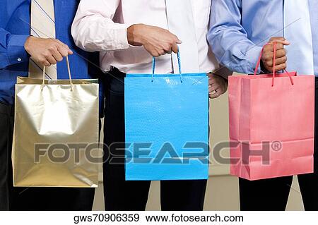 Mid section view of three businessmen holding shopping bags View Large Photo Image Stock Photo - Mid section view of three businessmen holding shopping bags. Fotosearch