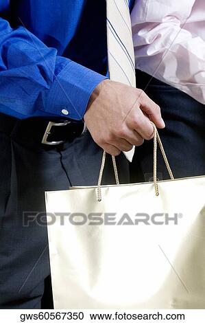 Stock Image - Mid section view of two businessmen holding shopping bags. Fotosearch