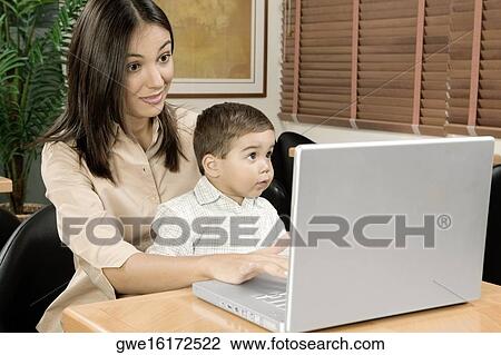 Mother using a laptop with her son View Large Photo Image Stock Image - Mother using a laptop with her son. Fotosearch