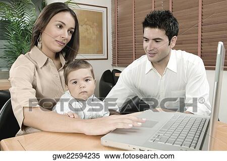 Portrait of a baby boy sitting in front of a laptop with his parents View Large Photo Image Stock Photography - Portrait of a baby boy sitting in front of a laptop with his parents. Fotosearch