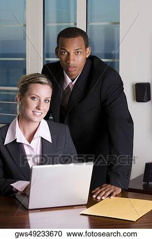 Portrait of a businessman and a businesswoman in front of a laptop View Large Photo Image Stock Image - Portrait of a businessman and a businesswoman in front of a laptop. Fotosearch