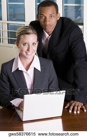 Portrait of a businessman and a businesswoman in front of a laptop View Large Photo Image Stock Photography - Portrait of a businessman and a businesswoman in front of a laptop. Fotosearch