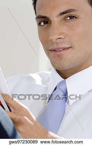 Portrait of a businessman holding a magazine View Large Photo Image Stock Photo - Portrait of a businessman holding a magazine. Fotosearch