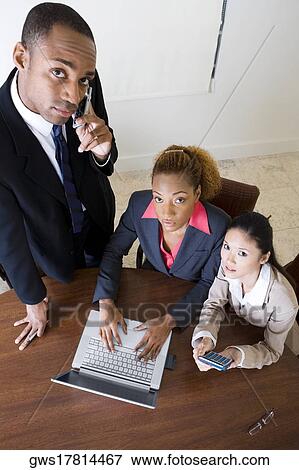 Portrait of a businessman talking on a mobile phone with two businesswomen sitting beside him View Large Photo Image Stock Photo - Portrait of a businessman talking on a mobile phone with two businesswomen sitting beside him. Fotosearch