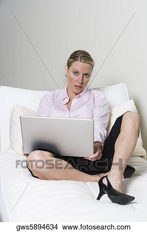 Portrait of a businesswoman sitting on the bed holding a laptop View Large Photo Image Picture - Portrait of a businesswoman sitting on the bed holding a laptop. Fotosearch