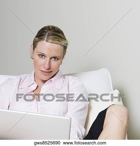 Portrait of a businesswoman sitting on the bed holding a laptop View Large Photo Image Stock Image - Portrait of a businesswoman sitting on the bed holding a laptop. Fotosearch