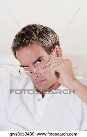 Portrait of a mid adult man adjusting his eyeglasses View Large Photo Image Stock Image - Portrait of a mid adult man adjusting his eyeglasses. Fotosearch