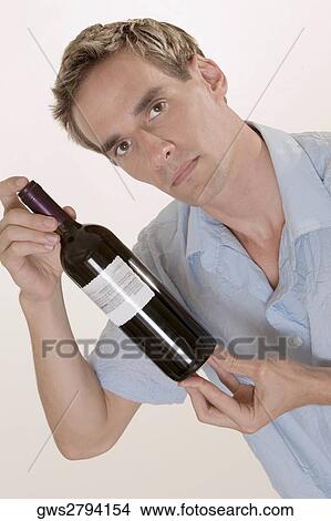 Portrait of a mid adult man holding a bottle of red wine View Large Photo Image Picture - Portrait of a mid adult man holding a bottle of red wine. Fotosearch