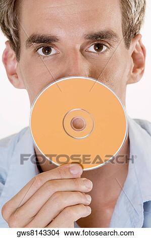 Portrait of a mid adult man holding a CD in front of his mouth View Large Photo Image Picture - Portrait of a mid adult man holding a CD in front of his mouth. Fotosearch