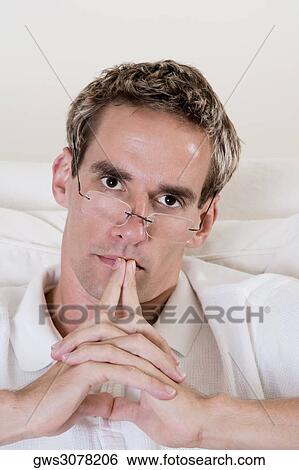 Portrait of a mid adult man sitting with his hands clasped View Large Photo Image Stock Photograph - Portrait of a mid adult man sitting with his hands clasped. Fotosearch