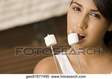 Stock Image - Portrait of a teenage girl eating marshmallows. Fotosearch