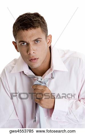Portrait of a young man adjusting his tie View Large Photo Image Stock Photography - Portrait of a young man adjusting his tie. Fotosearch