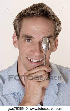 Portrait of a young man covering his eye with a spoon View Large Photo Image Stock Image - Portrait of a young man covering his eye with a spoon. Fotosearch