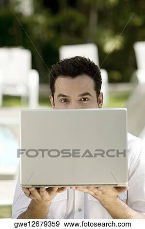 Stock Photo - Portrait of a young man holding a laptop. Fotosearch