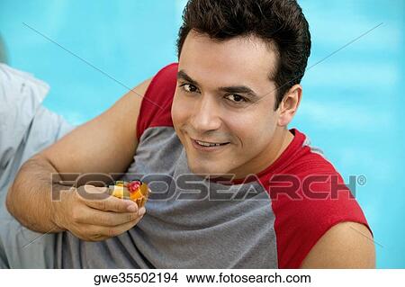 Picture - Portrait of a young man holding a cupcake. Fotosearch