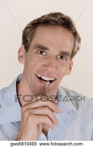 Portrait of a young man holding a spoon in his mouth View Large Photo Image Stock Image - Portrait of a young man holding a spoon in his mouth. Fotosearch