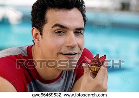 Portrait of a young man holding a cupcake View Large Photo Image Stock Image - Portrait of a young man holding a cupcake. Fotosearch