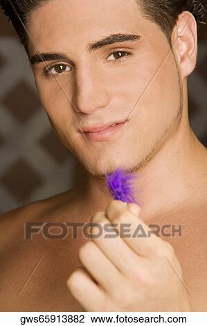 Portrait of a young man holding a feather View Large Photo Image Stock Image - Portrait of a young man holding a feather. Fotosearch