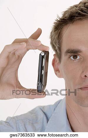 Portrait of a young man holding a mobile phone View Large Photo Image Stock Image - Portrait of a young man holding a mobile phone. Fotosearch