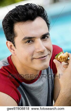 Portrait of a young man holding a cupcake View Large Photo Image Stock Photo - Portrait of a young man holding a cupcake. Fotosearch