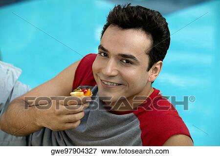 Portrait of a young man holding a cupcake View Large Photo Image Stock Photo - Portrait of a young man holding a cupcake. Fotosearch