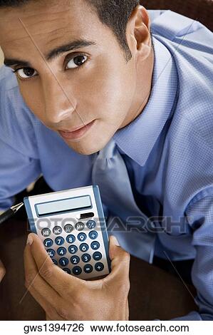 Portrait of a young man holding a calculator View Large Photo Image Stock Photograph - Portrait of a young man holding a calculator. Fotosearch
