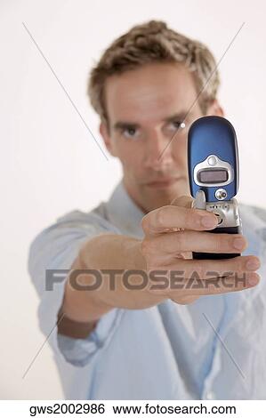 Portrait of a young man holding a mobile phone View Large Photo Image Stock Photograph - Portrait of a young man holding a mobile phone. Fotosearch